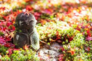 japanische jizo-skulpturpuppe mit fallendem rotem ahornblatt im japanischen garten am enkoji-tempel, kyoto, japan. Wahrzeichen und berühmt in der Herbstsaison foto