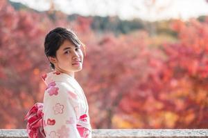 Junge Touristin im Kimono mit bunten Blättern im Kiyomizu-Dera-Tempel, Kyoto, Japan. asiatisches mädchen mit frisur in traditioneller japanischer kleidung in der herbstlaubsaison foto