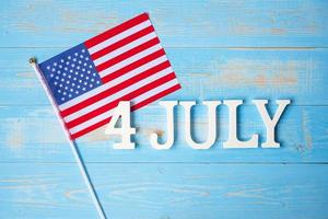 4. juli text und flagge der vereinigten staaten von amerika auf holztischhintergrund. usa feiertag der unabhängigkeit und feierkonzepte foto