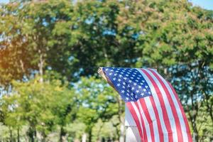 Frau, die mit der Flagge der Vereinigten Staaten von Amerika im Park im Freien reist. usa feiertag von veteranen, denkmal, unabhängigkeit und arbeitstagkonzept foto