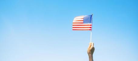 Hand, die die Flagge der Vereinigten Staaten von Amerika auf blauem Himmelshintergrund hält. usa feiertag von veteranen, denkmal, unabhängigkeit und arbeitstagkonzept foto