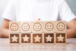 Emotionsgesicht und Sternsymbolblöcke auf Tabellenhintergrund. Servicebewertung, Ranking, Kundenbewertung, Zufriedenheit, Bewertung und Feedback-Konzept foto