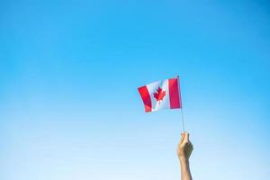 Hand, die Kanada-Flagge auf Hintergrund des blauen Himmels hält. kanada-tag und fröhliche feierkonzepte foto