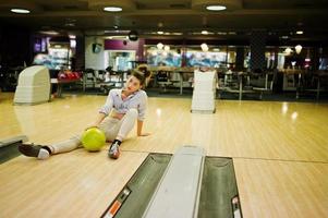 Mädchen mit Bowlingkugel auf der Gasse spielte im Bowlingclub. foto