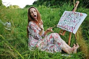Porträt eines lustigen Mädchens, das beim Malen auf der Wiese seltsame Gesichtsausdrücke macht. foto
