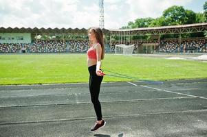 Fitness sportliches Mädchen in Sportbekleidung bei einem Fußballstadion im Freien. glückliches sexy frauentraining und springen mit seil. foto