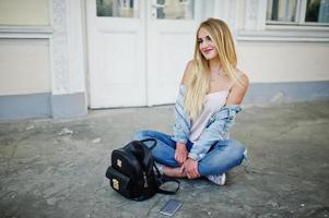 blonde Mädchen tragen Jeans mit Rucksack gegen alte Tür gestellt. foto