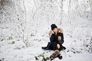 schönes brünettes Mädchen in warmer Winterkleidung. Modell auf Winterjacke und schwarzem Hut. foto