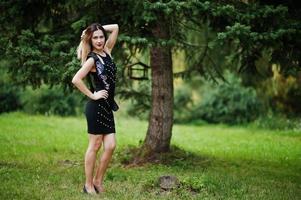 Porträt eines wunderschönen Mädchens, das beim Junggesellinnenabschied auf Schwarz trägt und im Park posiert. foto