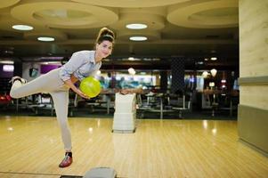 Mädchen mit Bowlingkugel auf der Gasse spielte im Bowlingclub. foto