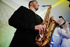 musikalische musik-live-band, die auf einer bühne mit verschiedenen lichtern auftritt. Saxophonist spielt. foto