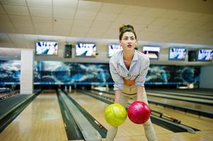 Mädchen mit Bowlingkugel auf der Gasse spielte im Bowlingclub. foto