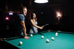 Frau im Kleid spielt Billard mit einem Mann in einer Kneipe. foto