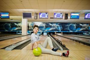 Mädchen mit Bowlingkugel auf der Gasse spielte im Bowlingclub. foto