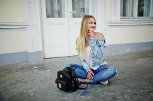 blonde Mädchen tragen Jeans mit Rucksack gegen alte Tür gestellt. foto