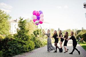 Fünf Mädchen tragen beim Junggesellinnenabschied Schwarz mit Luftballons. foto