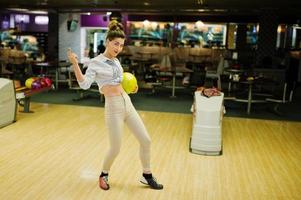 Mädchen mit Bowlingkugel auf der Gasse spielte im Bowlingclub. foto