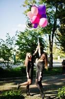 Zwei Mädchen tragen beim Junggesellinnenabschied Schwarz mit Luftballons. foto