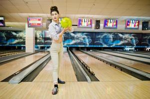 Mädchen mit Bowlingkugel auf der Gasse spielte im Bowlingclub. foto