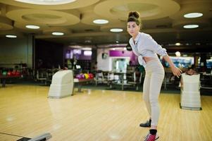 Mädchen mit Bowlingkugel auf der Gasse spielte im Bowlingclub. foto