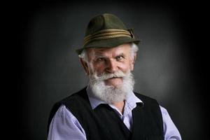 alter bayerischer Mann im Hut auf schwarzem Hintergrund foto