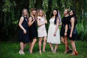 Gruppe von 6 Mädchen in Schwarz und 2 Bräute beim Junggesellinnenabschied. foto