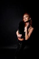Mode-Modell rothaariges Mädchen mit ursprünglich Make-up wie Leoparden-Raubtier isoliert auf schwarz. Studioportrait. foto