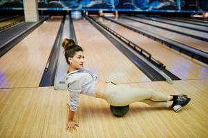 Mädchen mit Bowlingkugel auf der Gasse spielte im Bowlingclub. foto