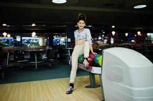 Mädchen mit Bowlingkugel auf der Gasse spielte im Bowlingclub. foto