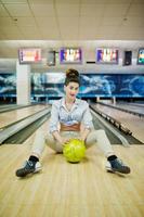 Mädchen mit Bowlingkugel auf der Gasse spielte im Bowlingclub. foto