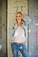 blonde Mädchen tragen Jeansjacke auf der Straße gestellt. foto