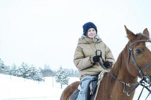 Ein Mädchen reitet im Winter auf einem Pferd. Winterferien foto