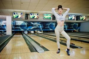 Mädchen mit Bowlingkugel auf der Gasse spielte im Bowlingclub. foto