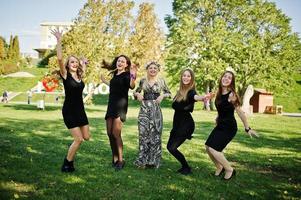 Fünf Mädchen tragen beim Junggesellinnenabschied schwarzes Springen. foto