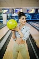 Mädchen mit Bowlingkugel auf der Gasse spielte im Bowlingclub. foto