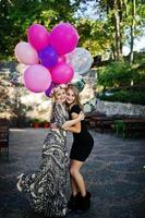 Zwei Mädchen tragen beim Junggesellinnenabschied Schwarz mit Luftballons. foto