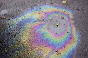 schillernder Benzinfleck. Benzin auf dem Asphalt eine große verschmutzte Wasserpfütze. ein Regenbogen Benzin foto