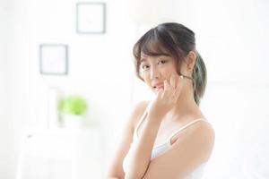 schönes porträt asiatisches frauenmake-up von kosmetik, mädchenhandberührungswange und lächeln attraktiv, gesichtsschönheit perfekt mit wellness im schlafzimmer mit hautpflege- und gesundheitskonzept. foto