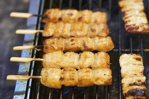 Nahaufnahme von Barbecue-Lachsspießen auf Holzstäbchen, thailändischer Straßenmarkt foto