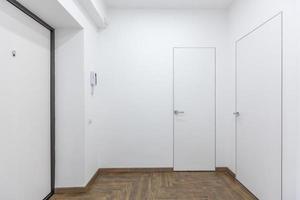 Korridor mit weißen Wänden und Türen in der Wohnung foto