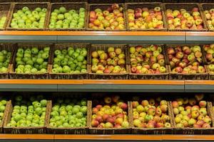 Regalboxen mit bunten Äpfeln im Supermarkt auf der Theke foto