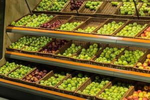 Regalboxen mit bunten Äpfeln im Supermarkt auf der Theke foto