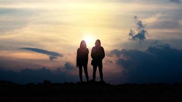 Silhouette von Liebeskerl und -mädchen gegen Sonnenuntergang foto