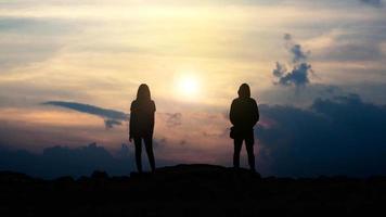 Silhouette von Liebeskerl und -mädchen gegen Sonnenuntergang foto