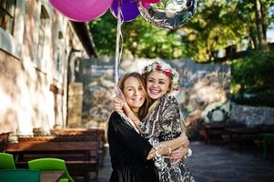 Zwei Mädchen tragen beim Junggesellinnenabschied Schwarz mit Luftballons. foto