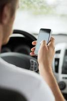 Nahaufnahme des Mannes mit Smartphone während des Autofahrens foto