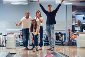 Sie können den Streik machen. Junge, fröhliche Freunde haben an ihren Wochenenden Spaß im Bowlingclub foto