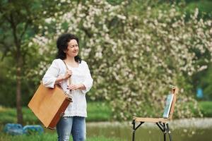 nur eine Person. reifer maler mit instrumentenkoffer spazieren im schönen frühlingspark foto