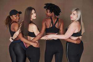 gesunder Lebensstil. Gruppe multiethnischer Frauen, die im Studio vor braunem Hintergrund stehen foto