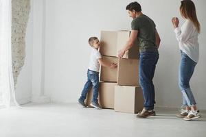 kleiner Helfer. Familie hat Umzug in neues Haus. Umzugskartons auspacken foto